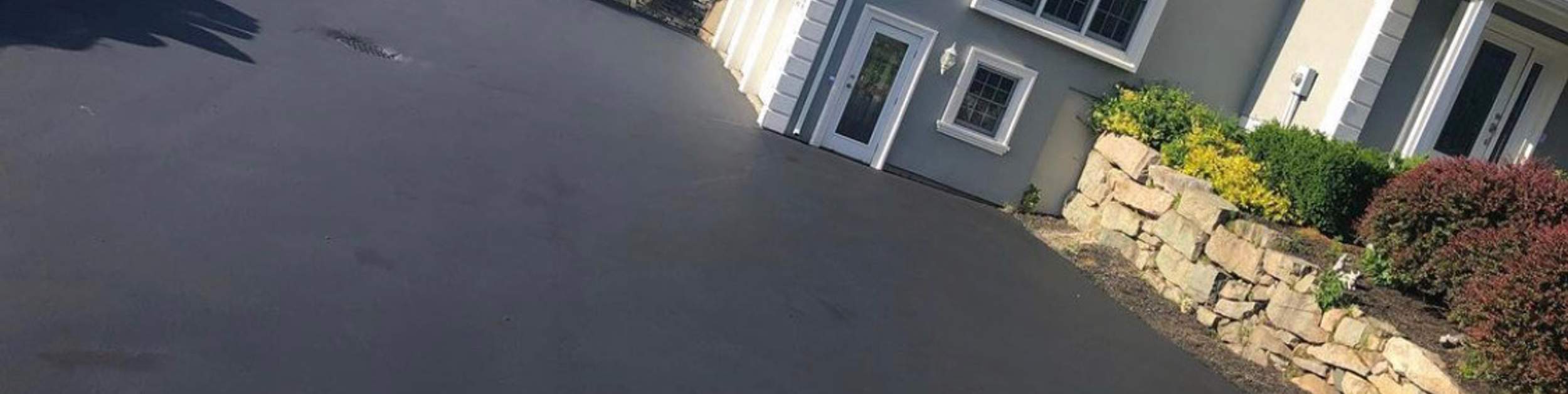 Sloped driveway lined by a natural stone retaining wall